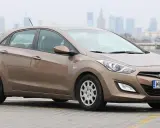Brązowy Hyundai i30 1.6 benzyna na parkingu z widokiem na miasto w tle.