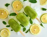 Trois bâtonnets glacés verts, comme une coupe colonel rafraîchissante, entourés de citrons, de menthe et de glaçons.