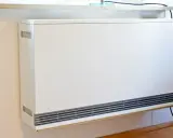 Ein weißer Nachtspeicherheizkörper an einer Wand. Der Austausch von Nachtspeicherheizungen ist Pflicht, um Energie zu sparen.