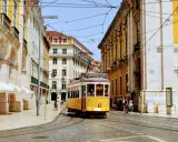 Gelber Oldtimer-Tram fährt durch Lissabon. Die Höchstgeschwindigkeit Portugals ist hier nicht relevant, aber die Atmosphäre ist unbezahlbar.