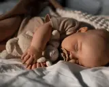 Bambino addormentato con peluche e ciuccio, forse in una fase di regressione del sonno.
