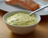 En skål med krämig romsås till lax, med dill och en sked redo att servera.