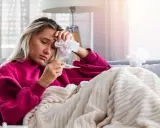 Donna malata con termometro e fazzoletto, preoccupata per il suo stato, forse **immunodepresso significato** da approfondire.