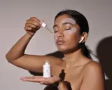 Donna applica siero con contagocce, ha maschera occhi e auricolari. Chissà ogni quanto maschera occhi per un viso radioso.