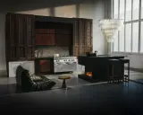 Ett kök med industriell känsla, inspirerat av Marie Olsson Nylander inredning. En stor gasspis, mörka träskåp och en modern köksö med eldstad.