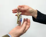Manos intercambian llaves, simbolizando un nuevo hogar o un contrato de subarrendamiento.