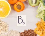 Napis "B3" na kartce otoczony przez pomarańczę, morele, kiwi, brokuły, płatki owsiane, grykę i płatki kukurydziane.