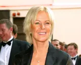 Anni-Frid Lyngstad, känd som Frida, ler med en hjärtformad halsband. Hon är klädd i en svart kavaj.