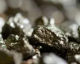 Zbliżenie na błyszczące bryłki pirytu, ukazujące jego metaliczny połysk i nierówną powierzchnię. Piryt właściwości tego minerału fascynują.