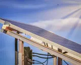 Ein Balkonkraftwerk MV fängt die Sonnenstrahlen ein. Der blaue Himmel mit Wolken und die Sonne im Hintergrund versprechen viel Energie.