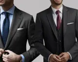 Two men showcase stylish charcoal suit combinations. One wears a patterned tie, the other a burgundy tie and vest.