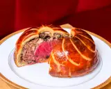Un pâté en croûte aux couches généreuses, un délice d'antan origine, sur une assiette blanche bordée d'or.
