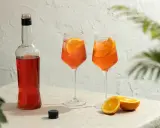 Butelka Aperolu i dwa drinki z pomarańczą, idealne proporcje na letnie popołudnie.