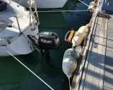 Un voilier "love love" amarré au ponton, avec un moteur Suzuki prêt à l'action. Des pare-battages protègent la coque.