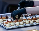 Mains de chef en gants noirs disposant des bouchées, une spécialité culinaire de Metz, sur un plateau.