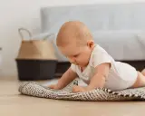 Dziecko na brzuchu, ćwiczy **wysoki podpór kiedy** na dywaniku.