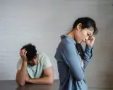 Pareja en silencio, ella con la mano en la frente, él con la cabeza entre las manos. Un ambiente de tensión pasivo agresivo.