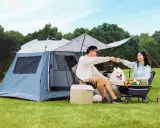 Para relaksu na biwaku z psem, z namiotem i stolikiem. Idealne jedzenie na biwak to świeże owoce i napoje.