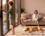 Hombre abre ventana, mujer trabaja en laptop en sofá, perro duerme. El ruido exterior, 40 dB es mucho ruido, interrumpe la paz.