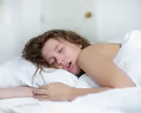 Junge Frau schläft tief und fest. Die Frage, wie oft atmet ein Mensch in der Minute, bleibt im Traum unbeantwortet.