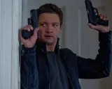 Jeremy Renner som Aaron Cross i rollistan i Jason Bourne-filmerna, redo för action med två pistoler.