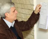 Mężczyzna z siwymi włosami pobiera z uchwytu wzór wypełnionego wniosku o rejestrację pojazdu.
