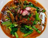 Un plat savoureux, un os de viande braisé dans une sauce riche, garni de radis et de légumes verts. Un aperçu des spécialités parisiennes.