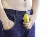 Mężczyzna w dżinsach trzyma banana, sugerując jelqing efekty.