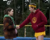 Una ragazza incinta e un ragazzo con fascia gialla si tengono per mano, scena tipica dei film d'amore adolescenziali.