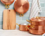 Utensilios de cobre apilados y colgados, listos para aprender como limpiar el cobre y mantenerlos brillantes.