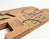 Stos papieru z recyklingu z nadrukiem nazwy marki i symbolami. Ekologiczne opakowanie na świecę.