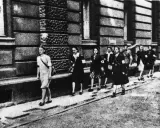 Kobiety w powstaniu warszawskim, idące ulicą. Na ramionach mają opaski.