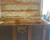 Proceso de restaurar baúl antiguo de chapa y madera. El interior muestra madera desgastada y papel tapiz despegado.