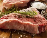 Bistecca alla fiorentina, un cibo succulento pronto per essere cucinato, con rosmarino, sale grosso e pepe.