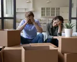 Couple overwhelmed by the stress of moving, surrounded by moving boxes.