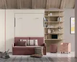 Sofá rosa con cojines, junto a una estantería y una **cama nido vertical** oculta.