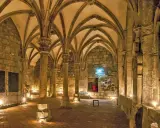 Gewölbte Gänge in einem **kloster mittelalter**. Säulen tragen das steinerne Dach, Kerzenlicht erhellt den Boden.
