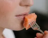Une personne mange un morceau de saumon à la fourchette. Un aperçu de son visage, idéal pour un avis sur le régime Natman.