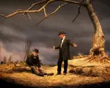 Due uomini, forse Vladimir ed Estragon, attendono Godot sotto un albero spoglio.