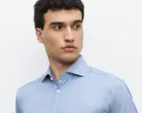 Mężczyzna w błękitnej koszuli z subtelnym wzorem i eleganckim kołnierzykiem włoskim.