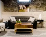 Gemütliches Wohnzimmer im industrial style mit dunklem Sofa, Holztisch und Steinwand.