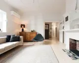Salon lumineux avec canapé, fauteuil, buffet en bois et cheminée. Idéal pour savoir comment trouver un appartement rapidement.