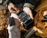 Un homme charge son téléphone avec une batterie externe, une aide précieuse pour comment organiser son téléphone et ses photos en voyage.