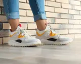 Białe sneakersy z żółtymi i czarnymi akcentami, idealne do jeansów. Czy to HOFF buty? Co to za firma?