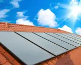 Fakta om solceller: Solpaneler på ett tegeltak fångar solens energi under en klarblå himmel med moln.