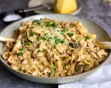 En krämig kyckling svamp pasta i en skål, toppad med persilja och parmesan.