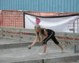 Jeune fille lançant une boule sur un terrain de pétanque, peut-être pour une partie de boule bretonne.