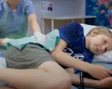 Sjukvårdare undersöker en pojke som ligger på en brits. Frågan om hjärnhinneinflammation hur länge är viktig för att förstå sjukdomsförloppet.