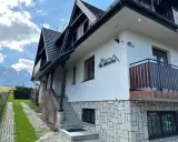 Willa Na Wierchu w Zakopanem, z kamienną podmurówką i drewnianymi elementami, wita gości pod malowniczymi Tatrami.