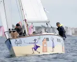 Un bateau muscadet décoré de personnages fantaisistes navigue sur l'eau, avec deux hommes à bord.
